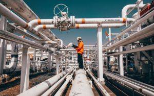 Worker Inspecting Pipes At Refinery